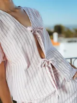 Camisa rosada a rayas verticales grises, con escote en V, mangas 3/4 voluminosas y cierre con lazo.