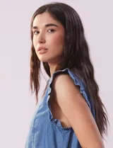 Blusa celeste de lyocell con cuello camisero, abertura con botones y volados en las sisas.