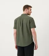 Camisa de hombre de manga corta en lino color blanco, con cuello clásico, botonadura frontal y bolsillo de parche en el pecho. Corte recto.