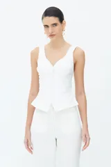 Blusa de algodón color blanco roto con tirantes anchos y corte en el busto, elástico en los tirantes para ajustar, bajo ancho y cierre con botones forrados.