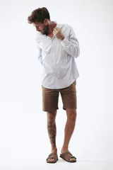 Camisa celeste a rayas verticales blancas, de corte clásico, manga larga y cuello abotonado.