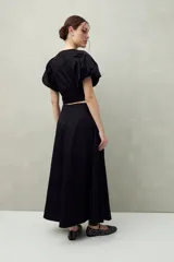 Falda midi blanca con pequeños lunares negros, de corte acampanado y cintura alta con pliegues.