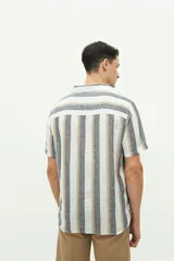 Camisa de manga corta confeccionada en lino y algodón a rayas verticales en tonos blanco, gris y beige. Tiene cuello tipo cubano, corte regular y logo bordado en el pecho.