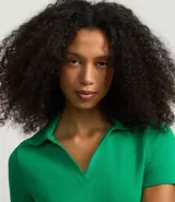 Blusa de punto acanalado (rib) color marrón oscuro, con cuello polo, escote en V y manga corta.