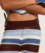 Pantalón femenino de punto con efecto crochet, de corte flare, cintura elástica y rayas horizontales en diferentes anchos y colores (azul claro, azul medio, bordó y blanco).