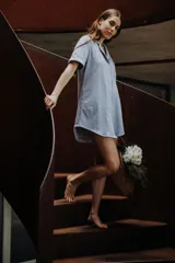 Camisa corta color rosa claro, de manga corta, con cuello camisero y cierre frontal con botones.