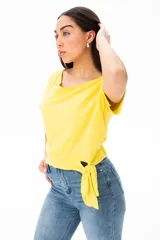 Remera amarilla de algodón y elastano, con escote redondo y mangas cortas. Presenta un nudo lateral en la cintura.