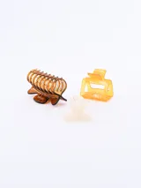 Set de tres pinzas para el pelo de diferentes diseños y colores: una pinza tipo garra color marrón, una pinza cuadrada color naranja y una pinza con forma de moño color crema.