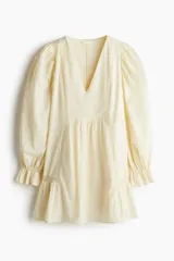 Vestido corto color crema en tejido liviano de algodón con inserciones de encaje, escote en V y mangas largas abullonadas con elástico en la muñeca y puños acampanados.
