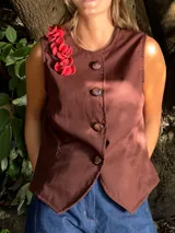 Chaleco marrón con botones y detalle de flores rojas en el hombro.