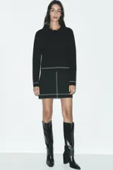 Chaqueta corta negra de punto con cuello solapa, manga larga y cierre frontal con botones.