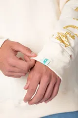 Buzo negro de corte oversize con cuello redondo y mangas largas. Presenta un pequeño logo estampado en el pecho y un diseño de empanadas y textos en la manga.