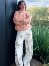Sweater tejido grueso color rosa, con cuello alto, mangas largas y diseño trenzado con detalles de pompones.