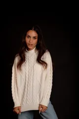 Sweater tejido de punto color rosa pastel, con cuello alto y diseño de trenzas verticales.