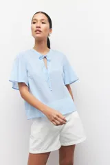 Blusa celeste a rayas verticales con cuello mao, mangas cortas y lazo en el frente.
