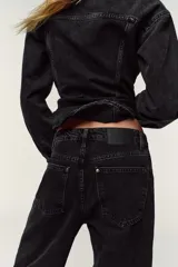 Pantalón de jean negro con lavado gastado, corte culotte, tiro alto, bolsillos delanteros y traseros, y cierre frontal con cremallera y botón.