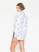 Camisa blanca de poplin con lycra y estampado de hongos en azul. Tiene ojales color bordó en la cartera y puños, y costura de refuerzo en forma de X en el puño.