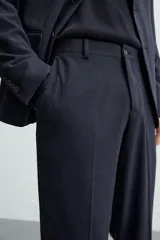Pantalón de vestir azul marino, de corte slim fit, confeccionado en tejido con 17% de lana. Cuenta con bolsillos frontales y traseros de doble vivo con botón. Cierre frontal con cremallera y botón.