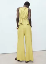 Pantalón de tiro alto, diseño recto y largo, color amarillo claro con finas rayas verticales. Presenta cierre de botón y cremallera, detalle de pinzas y dos bolsillos laterales.