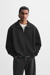 Sudadera negra de cuello alto con cierre frontal de cremallera, corte relaxed fit, manga larga y terminaciones en rib.