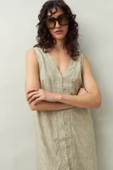 Vestido corto con estampado geométrico en tonos beige y blanco, con escote en V, sin mangas y cierre frontal con botones.