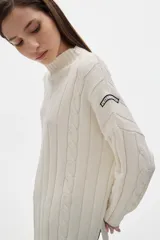 Sweater tejido color borgoña con cuello alto, corte oversize y mangas largas con detalle de trenzas verticales.