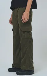 Pantalón cargo de corderoy color verde militar, de calce regular y diseño unisex. Presenta cintura elástica, bolsillos laterales y bolsillos tipo cargo con solapa en los laterales de las piernas.