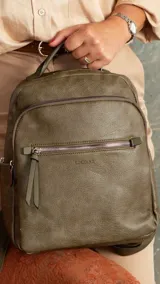 Mochila color caramelo de símil cuero, con dos bolsillos frontales con cierre y bolsillos laterales abiertos. Interior forrado con dos bolsillos con cierre y uno abierto. Tiene asa de mano y correas regulables.