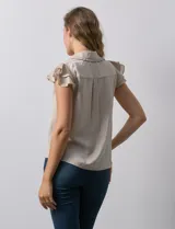 Camisa color beige de satén, con cuello con solapa y escote en V. Tiene una apertura central con botones y sisas con volados.