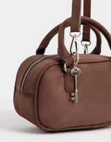 Cartera bowling color marrón chocolate, de cuero sintético, con doble asa corta, correa larga regulable y desmontable, y charm colgante.