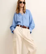 Pantalón wide leg color beige confeccionado en sarga sastrería, de cintura alta, sin estampa y con bolsillos cargo en los laterales.