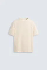 Camiseta color crema de corte relaxed fit, confeccionada en tejido de algodón compacto con estructura piqué. Cuello redondo y manga corta.