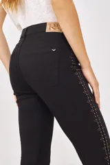 Pantalón jean slim negro con tachas plateadas en los laterales.