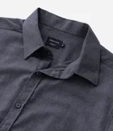 Camisa de manga larga color blanco, confeccionada en tricolina de algodón con efecto melange. Tiene cuello inglés, abotonado delantero y puños con botones.