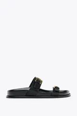 Sandalias planas negras con dos tiras anchas y hebillas doradas.