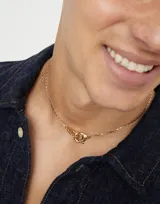 Collar dorado con dije de mosquetón entrelazado.