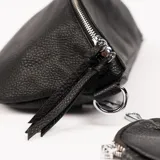 Riñonera negra de cuero con correa de tela estampada y monedero redondo con cierre.