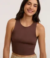 Top cropped sin mangas, color marrón oscuro, de corte ajustado al cuerpo y cuello redondo. Presenta textura acanalada.