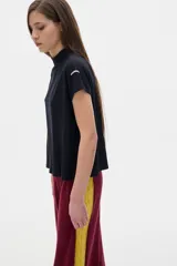Blusa negra de rib con cuello subido y mangas cortas.