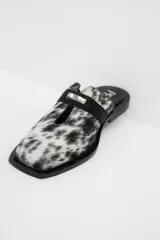 Zuecos con estampado animal print en blanco y negro, con tira ancha de cuero negro y aplique metálico.