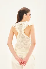 Musculosa tejida en hilo de algodón con punto desagujado, de calce al cuerpo y volados en las sisas.