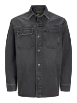 Sobrecamisa de denim negro con fit holgado, cuello tipo camisa, mangas largas y cierre con botones. Tiene bolsillos con tapa y botón en el pecho.