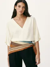 Blusa color crema con escote en V y mangas cortas amplias.