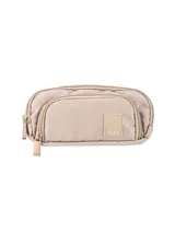 Set de tres piezas de accesorios de nylon color beige claro, compuesto por una mochila con bolsillo frontal, una lonchera con asa superior y una cartuchera pequeña con cierre. Todos los artículos tienen un diseño minimalista y liso, con una pequeña etiqueta de cuero sintético con el nombre de la marca.