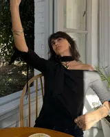 Collar con dije dorado irregular con agujero central, colgando de cordón negro ajustable.