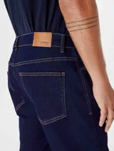 Pantalón de jean azul oscuro, de corte recto, con bolsillos laterales y traseros.