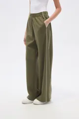 Pantalón deportivo negro de corte ancho y tiro alto, con cintura elástica y cordón ajustable. Presenta una raya blanca vertical a cada lado.