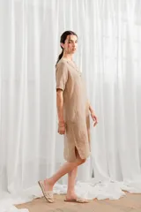 Vestido color beige de lino, de corte recto, con mangas cortas y escote en V con detalle de encaje.