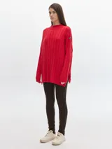 Buzo de punto en color gris con cuello alto, diseño oversized y cortes laterales.