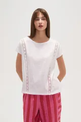 Remera blanca de algodón con apliques de encaje en los hombros, corte holgado y cuello redondo.